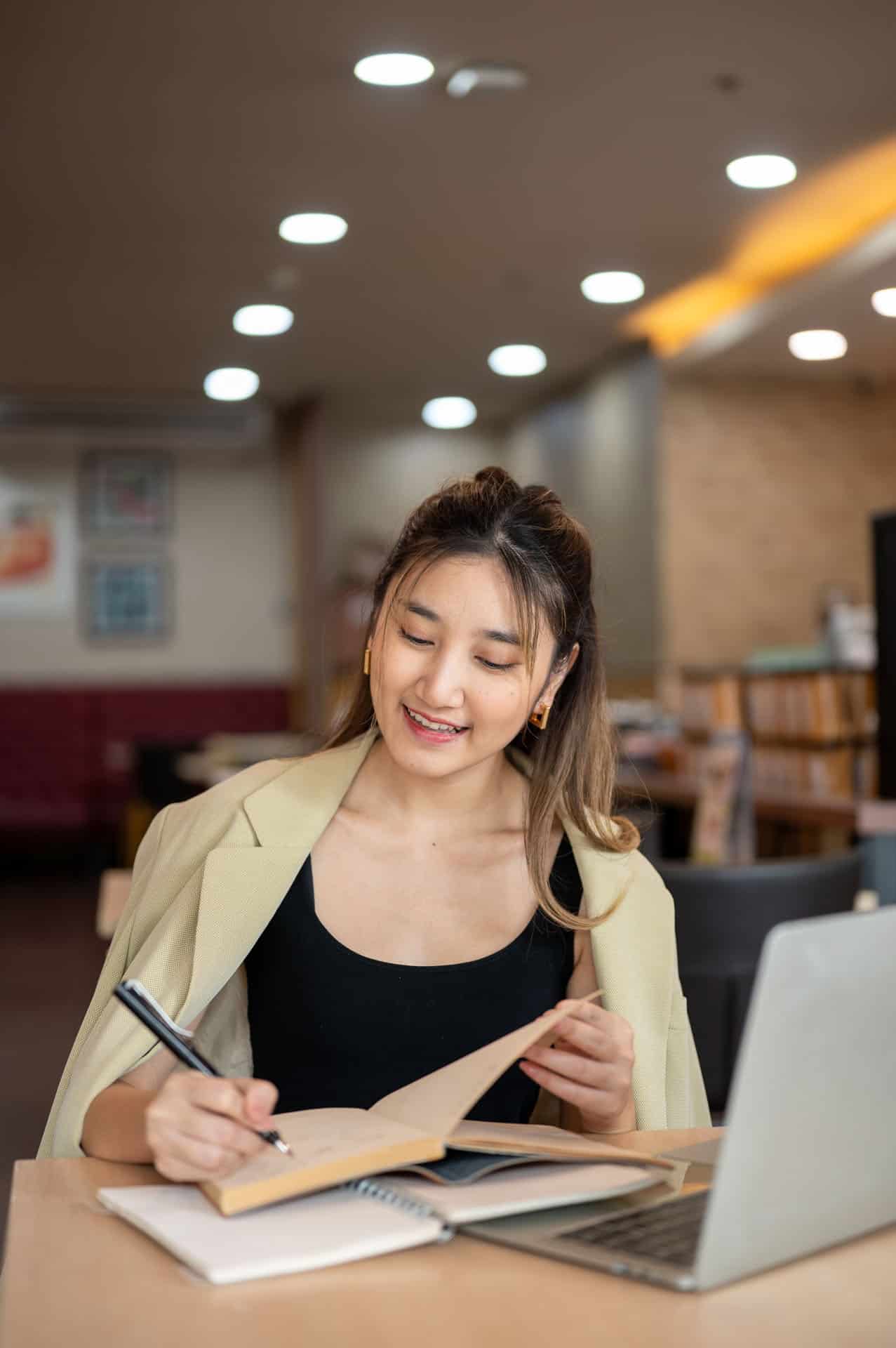 International student reviewing and signing enrollment documents at a desk with a laptop